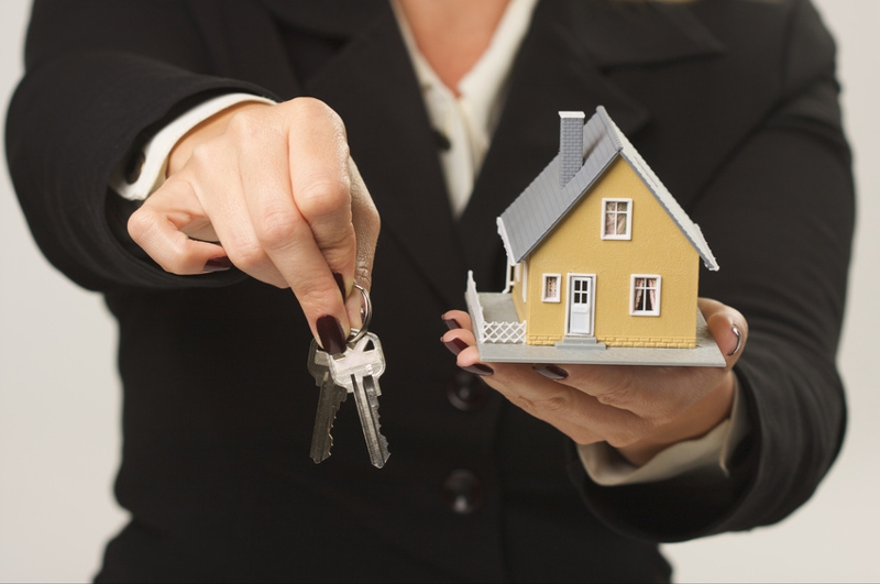 Female presenting keys and small house.